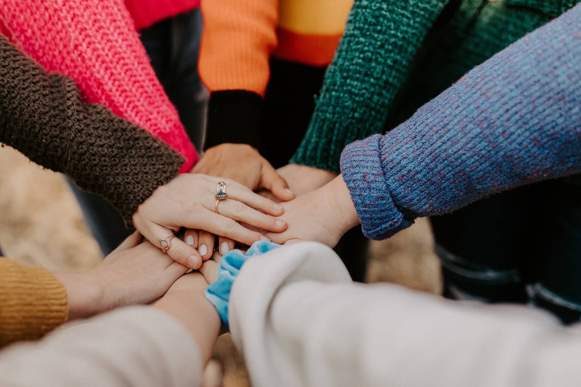 Eight people putting their hands on top of each other in the middle of a circle